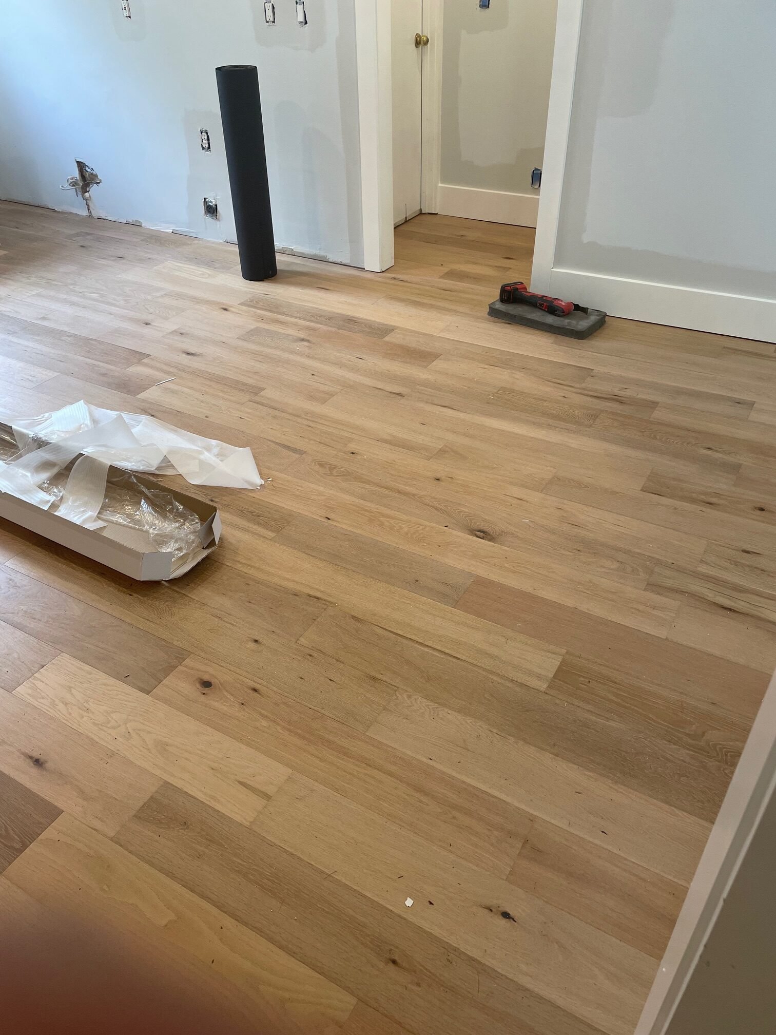 New hardwood flooring installation in progress with trim and baseboards unfinished