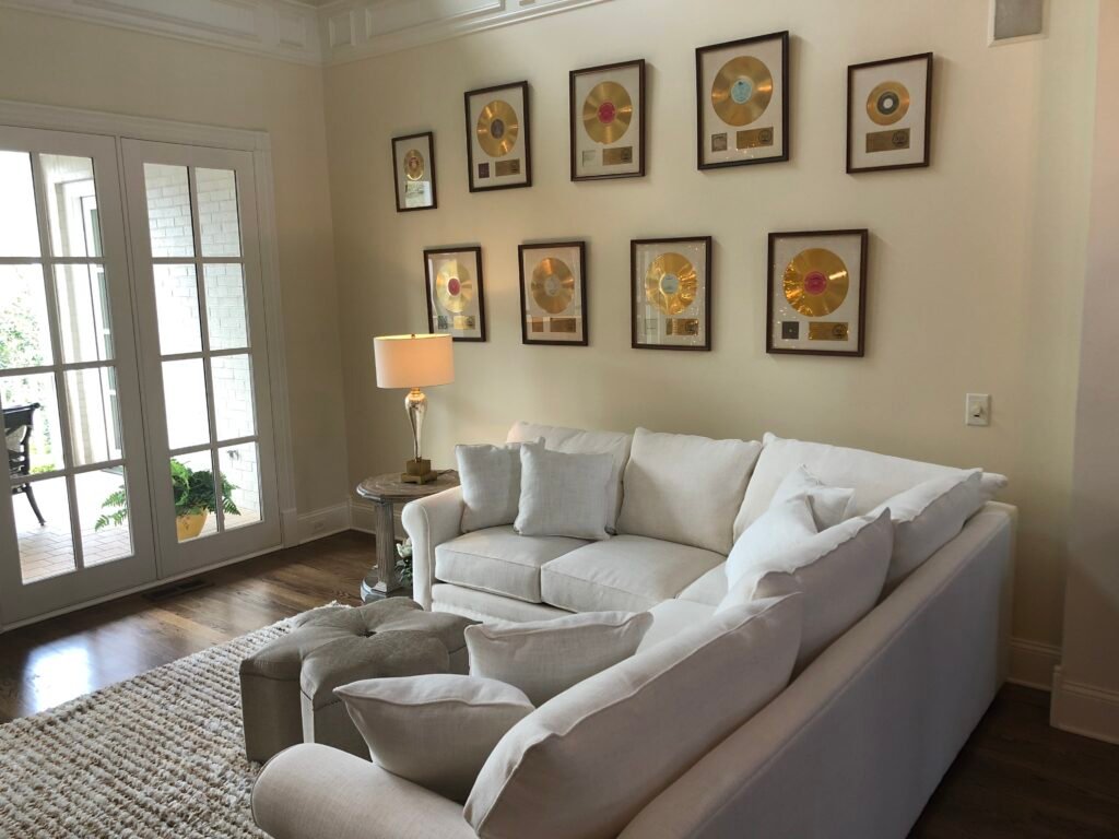 Elegant living room with framed gold records, bright white sofa, and natural light through French doors