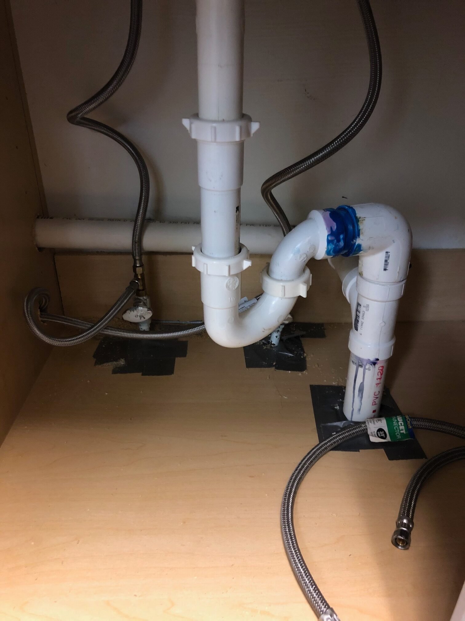 Under-sink plumbing repair showing PVC drain pipes and connections